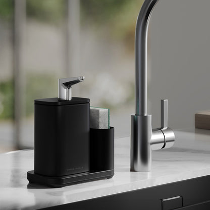 Simplehuman Matte Black Pulse Pump with caddy on kitchen sink edge, sponge in caddy on marble counter top.