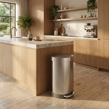 Simplehuman's Semi-Round Step Can in a modern kitchen setting with wooden cabinets and marble countertop.